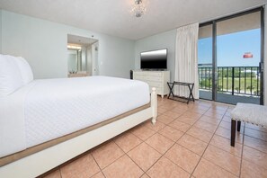 A bedroom with a bed, a TV, a balcony with a view, and a bathroom with a mirror. - Phoenix I 1071 3 Bedroom Condo (Orange Beach)