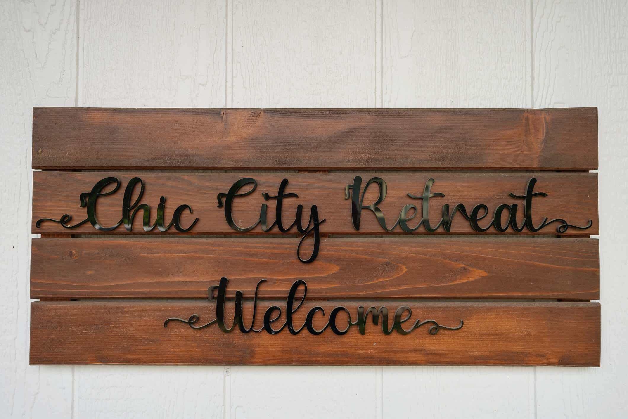 Ein hölzernes Schild mit der Aufschrift 'Chic City Retreat Welcome'.