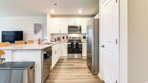 Una cocina moderna con armarios blancos, electrodomésticos de acero inoxidable y piso de madera.
