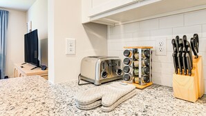 Una cocina con un tostador, un bloque de cuchillos y un juego de guantes de horno sobre la encimera.