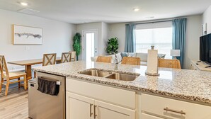 Una cocina moderna con encimeras de granito, pileta de acero inoxidable y lavavajillas integrado.