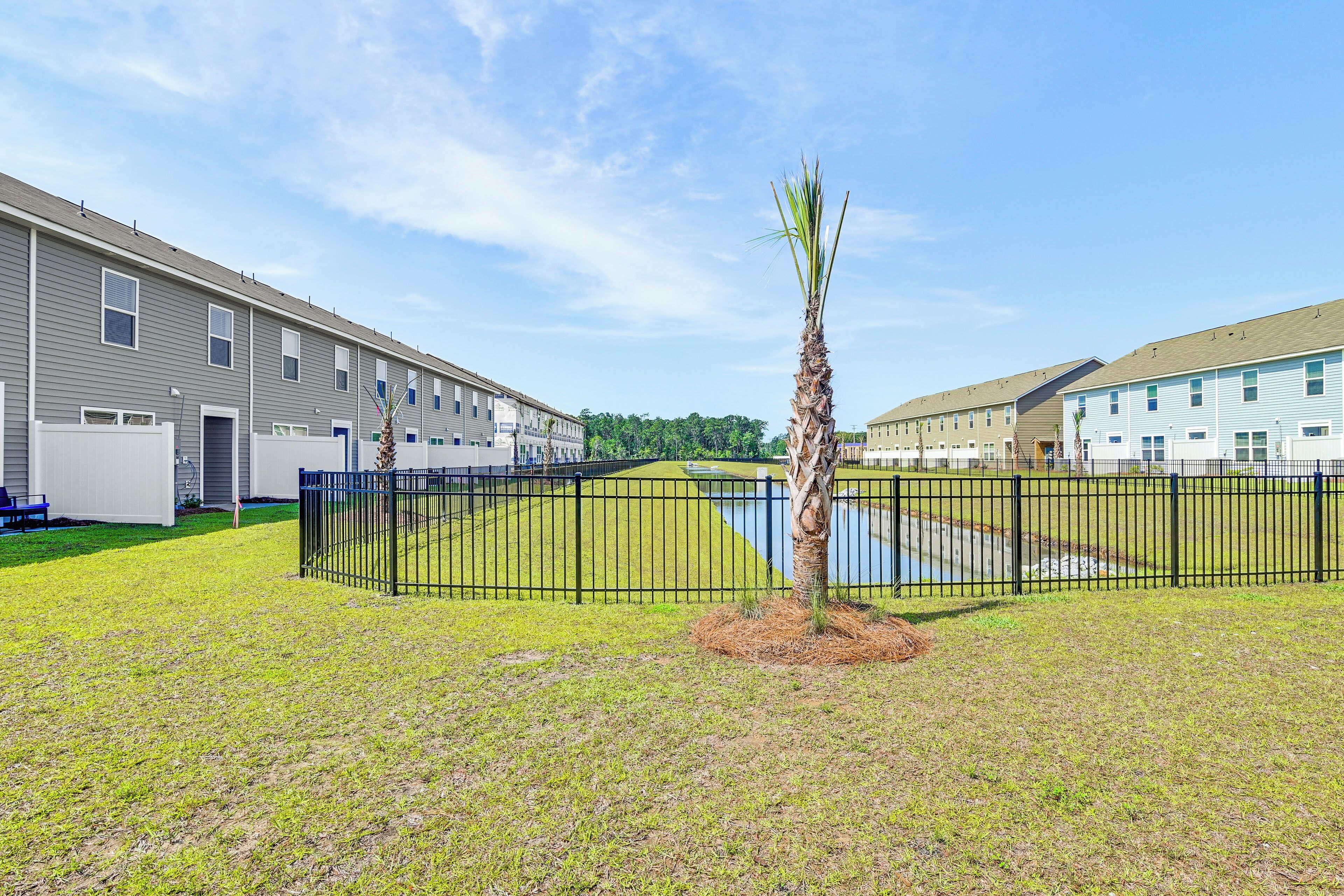 A residential building with a fenced courtyard, a small pond, and a palm tree.
