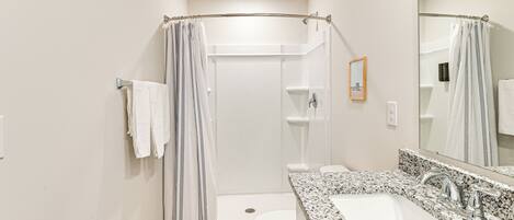 A bathroom with a shower, toilet, and sink.