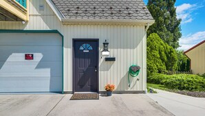 A residential garage with a closed door, a 'No Parking' sign, a welcome mat, and a potted plant. - Walk to Town: Charming Unit w/ Balcony in Bedford! (Bedford)