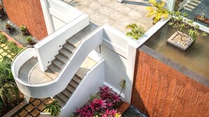 A spiral staircase with a glass railing, surrounded by potted plants and a small water feature. - Modern 2bhk w Pool Access 5km to Coco Beach (Nerul)