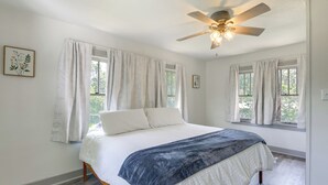 A bedroom with a bed, two windows with curtains, a ceiling fan, and a framed picture on the wall. - 4 Mi to Dtwn: Charming Retreat in Wichita! (Wichita)