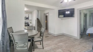 A modern kitchen with white cabinets, a dining area with a round table and chairs, a ceiling fan, and a TV mounted on the wall. - 4 Mi to Dtwn: Charming Retreat in Wichita! (Wichita)
