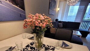 A dining area with a table set for two, a vase of flowers, and a painting on the wall. - Apartment in Winterberg Near Ski Lifts (Winterberg)