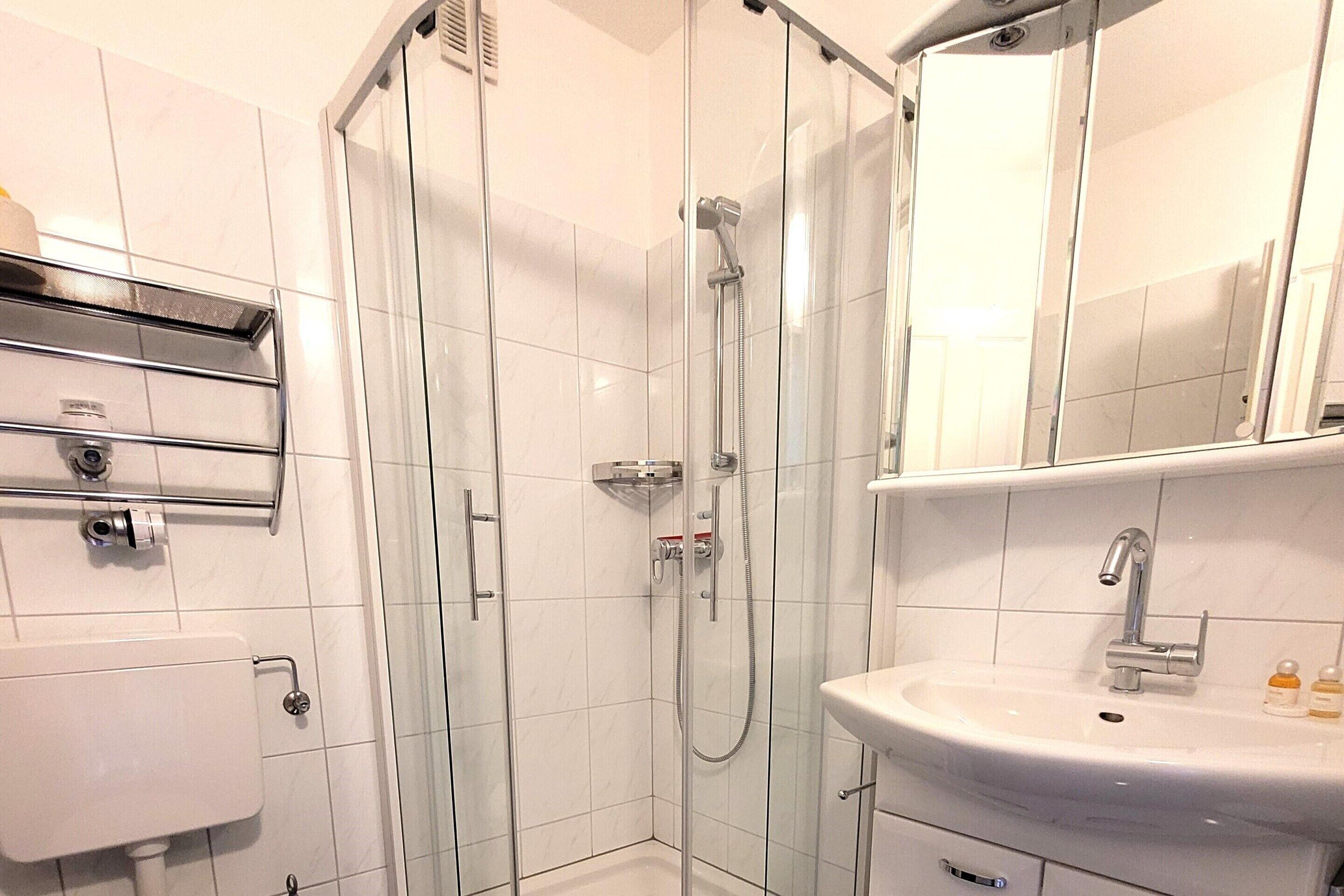 A modern bathroom with a glass-enclosed shower, a white sink, and a mirror above the sink.