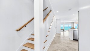 Ein modernes Interieur mit einer Holztreppe, einer Küchenzeile und Meerblick.