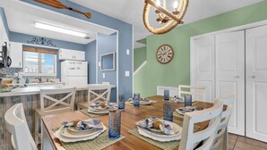 A dining area with a wooden table set for four, white chairs, and a chandelier.