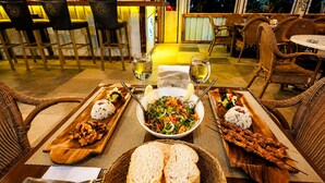 A restaurant setting with a table set for two, featuring a variety of dishes including rice, grilled chicken, skewered meat, and a salad. - Fİİ SUİTS (Kumluca)