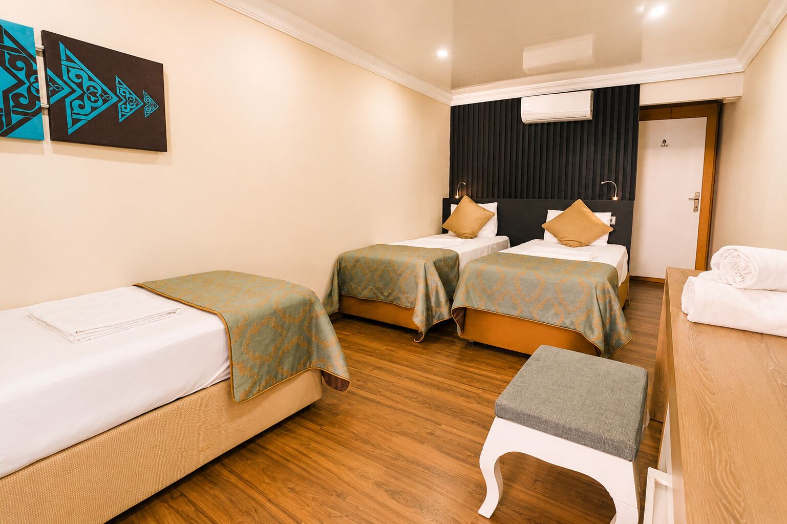 Ein Hotelzimmer mit zwei Einzelbetten, einem kleinen Tisch und einer Bank.