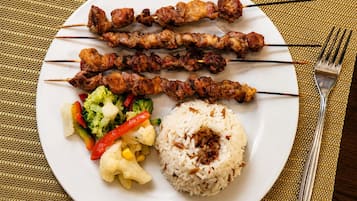 Une assiette contenant des brochettes, du riz et des légumes variés.