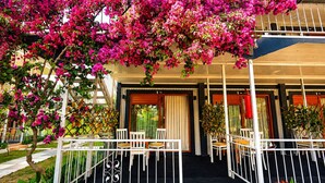 A hotel with a covered outdoor seating area, a staircase, and a view of the street. - Fİİ SUİTS (Kumluca)