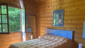 Een slaapkamer in een houten hutje met een groot bed, een raam en een ingelijste foto aan de muur.