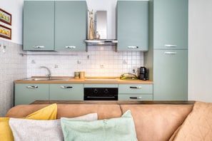 Una cocina con armarios verde mar, una encimera de madera y un lavavajillas negro.
