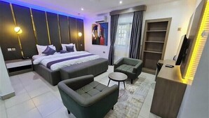 Een moderne hotelkamer met een groot bed, twee banken, een kleine tafel en een televisie.