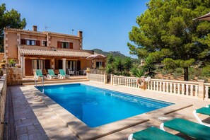 A swimming pool with lounge chairs, a stone pathway, and a building with a tiled roof. - "Es Turo de França" with Mountain Views, Pool, and Wi-Fi (S'Horta)
