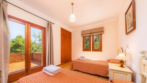 Habitación de hotel con dos camas, un balcón, un armario de madera y una ventana con cortinas.