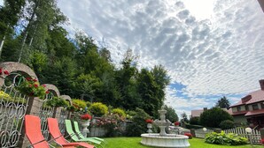 A well-maintained garden with a fountain, green lawn, and a white picket fence. - Pensjonat Miranda (Polanica-Zdrój)