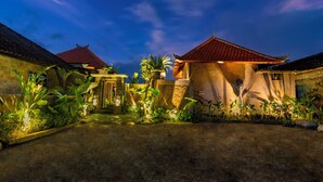 A traditional building with a red-tiled roof, surrounded by lush greenery and a well-maintained garden. - Seelong Villa Ubud by Dhananjaya Hospitality (Sebatu)