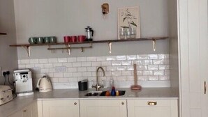 A kitchen with white cabinets, a white countertop, a sink, and a backsplash. - City Victorian Townhouse Cork, Kennedy Park (Cork)