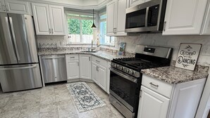 Una cocina moderna con armarios blancos, electrodomésticos de acero inoxidable, encimera de granito y una alfombra decorativa.