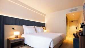A modern hotel room with a large bed, bedside tables, a desk, and a chair.