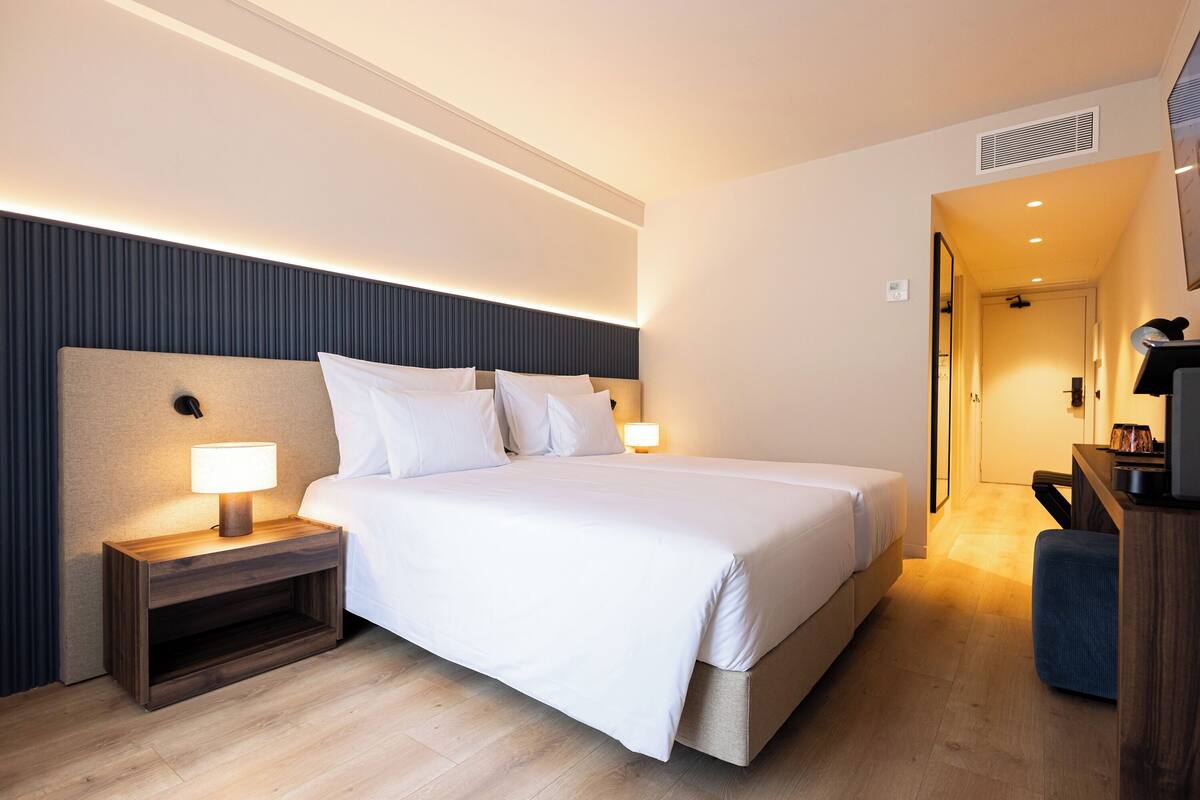 Een moderne hotelkamer met een groot bed, nachtkastjes, een bureau en een stoel.