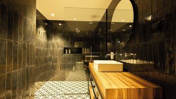 A modern bathroom with a large mirror, a wooden vanity, and a geometric patterned floor.