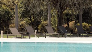 A pool area with lounge chairs and a clear blue pool.