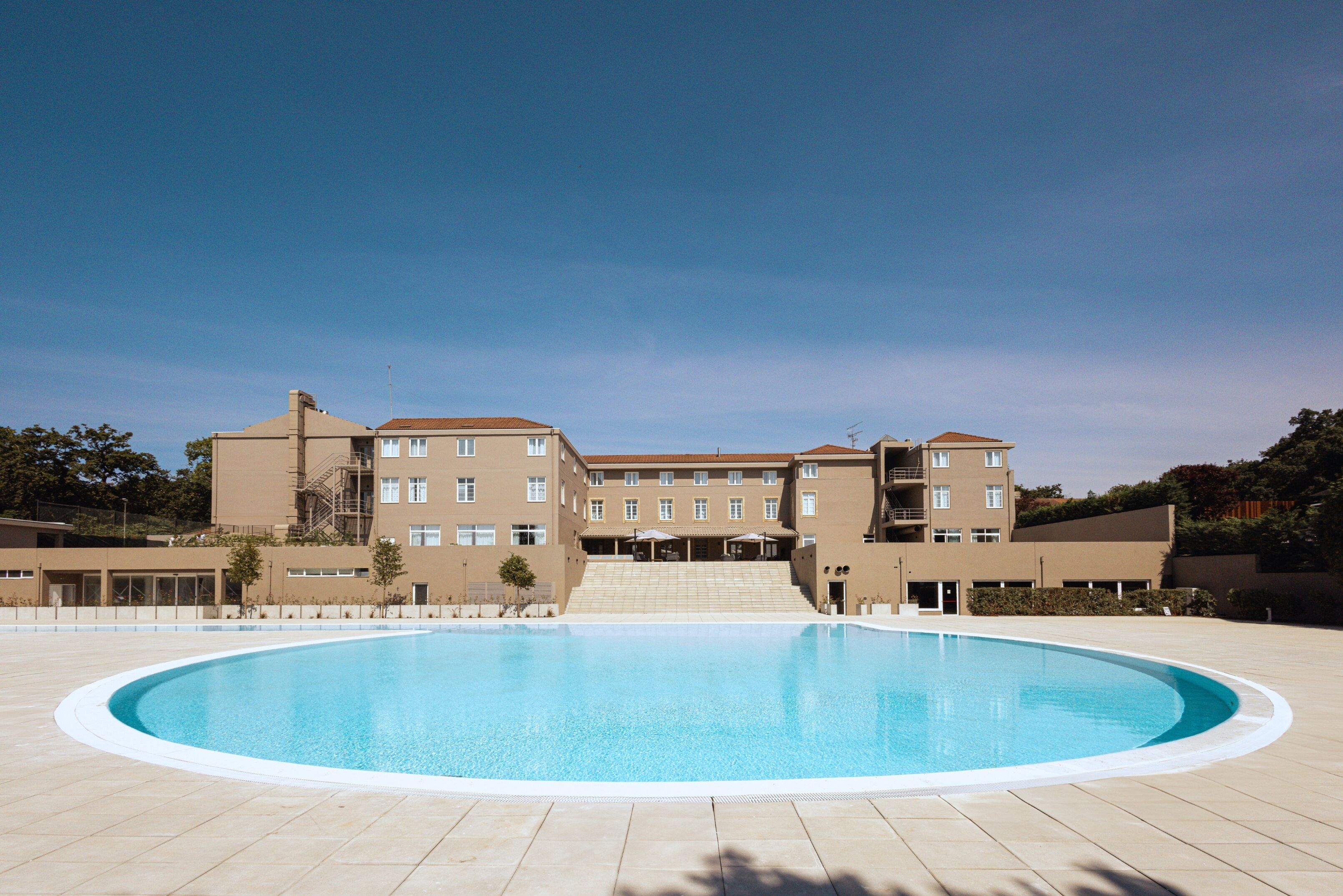 Ein großer, leerer Swimmingpool unter blauem Himmel.