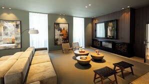 A modern living room with a sofa, two round coffee tables, a TV, and artwork on the walls.