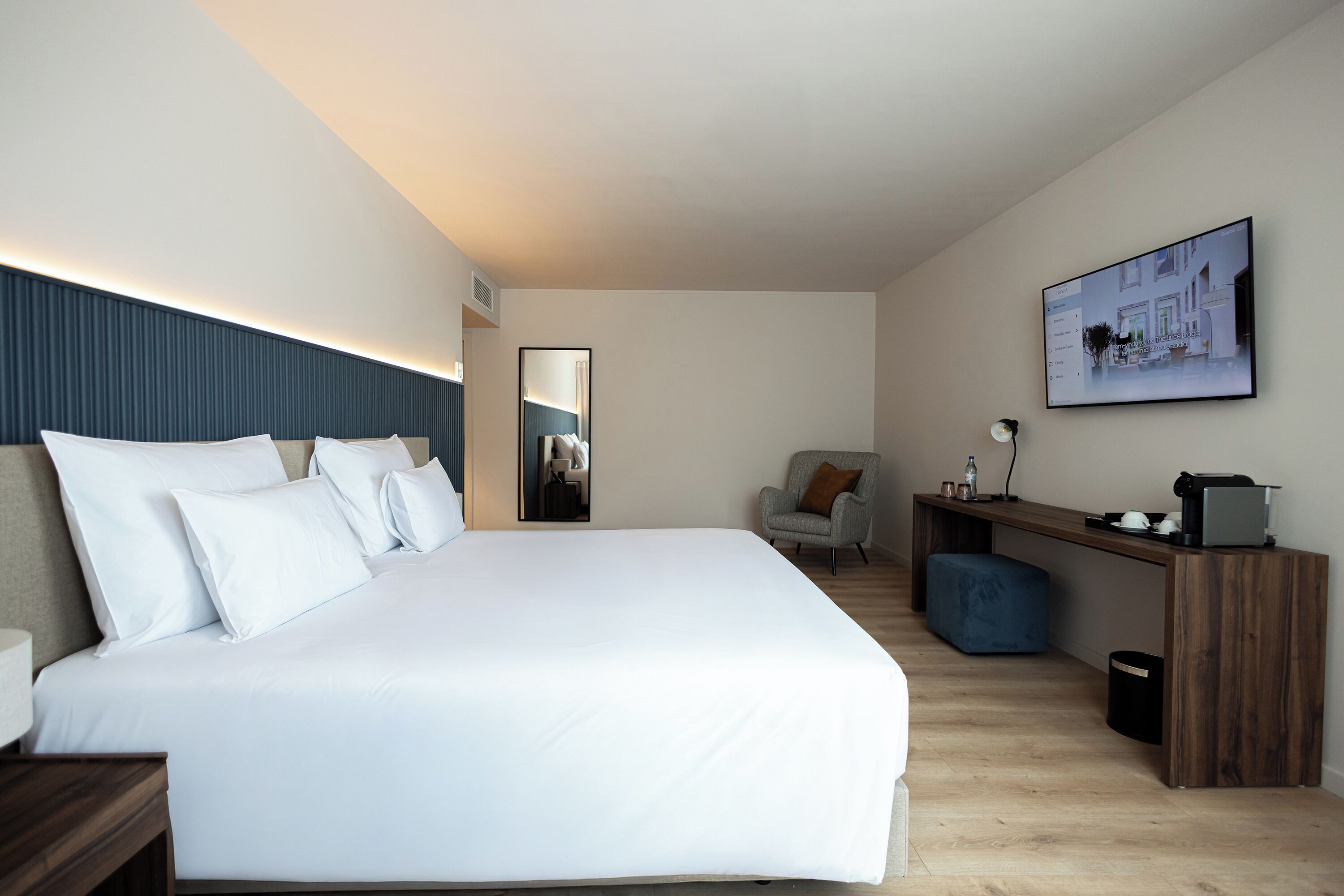 Een moderne hotelkamer met een groot bed, een bureau, een stoel en een groot raam.