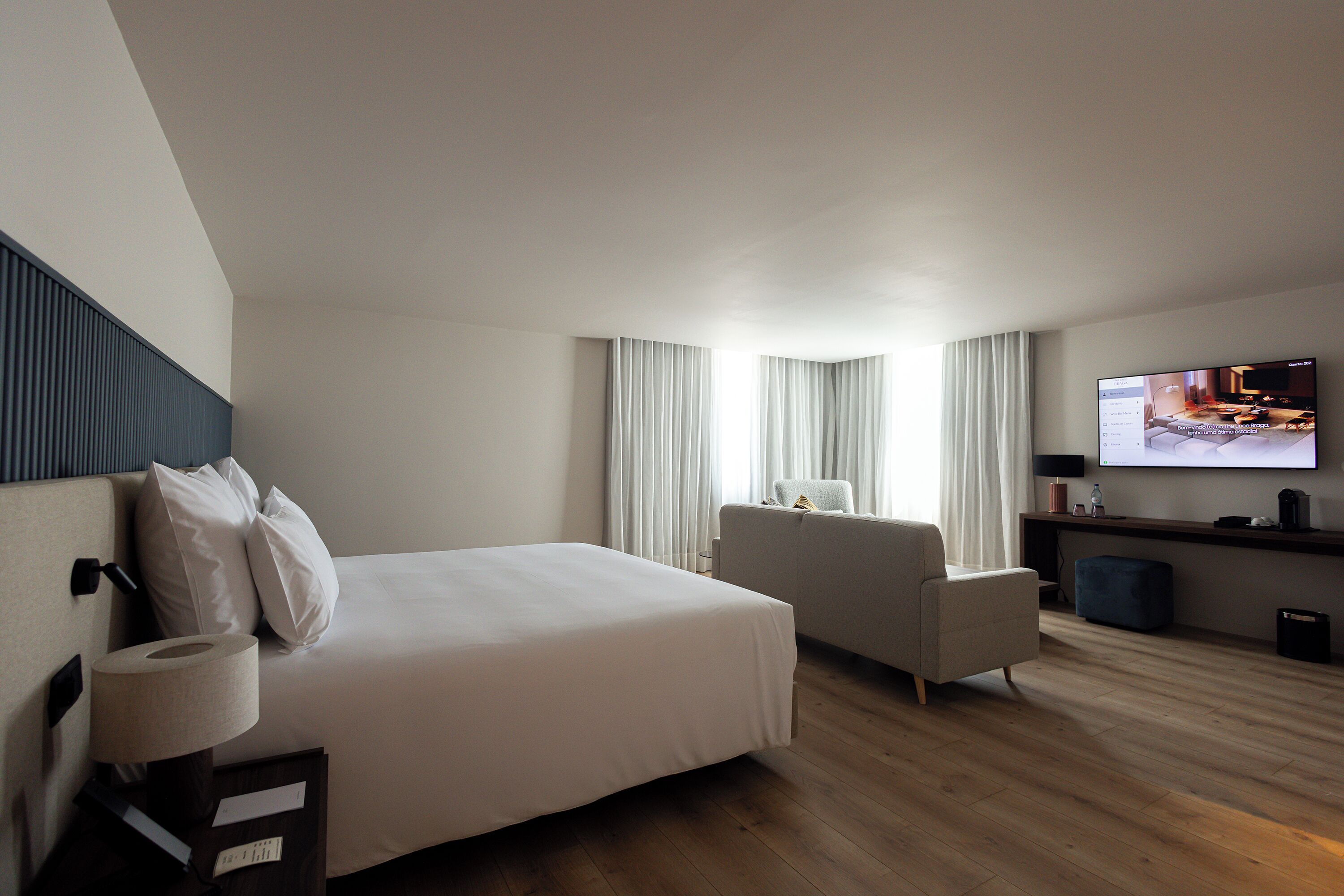 Habitación de hotel con cama, una silla, televisor y escritorio.