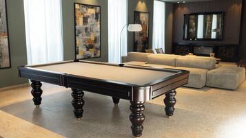 A pool table in a room with a sofa and a fireplace.