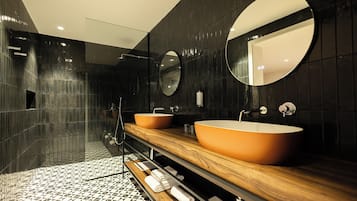 Un baño moderno con dos lavamanos ovalados, un mueble de tocador de madera y un espejo grande.