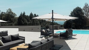 A rooftop terrace with outdoor seating, a pool, and a view of the surrounding landscape.