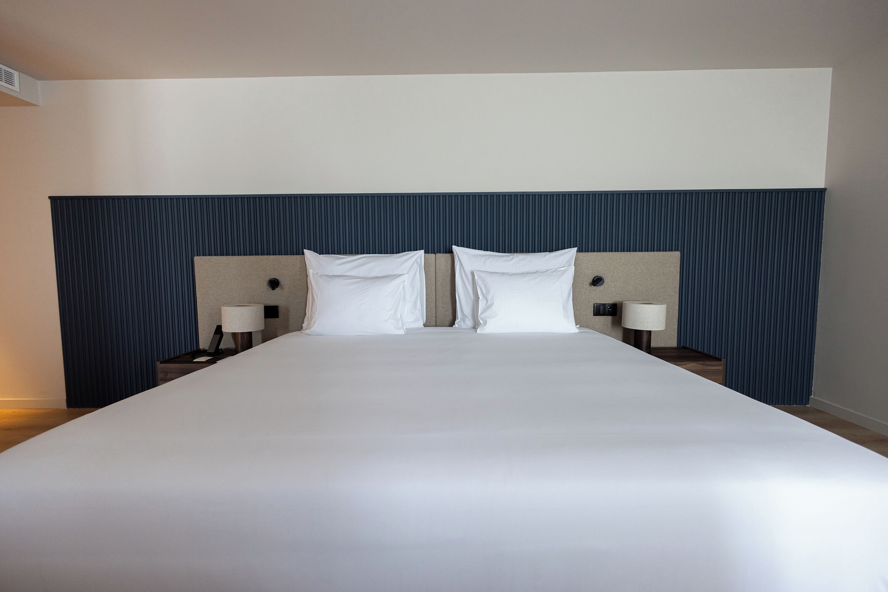 A large bed with a headboard, two bedside tables, and two lamps.