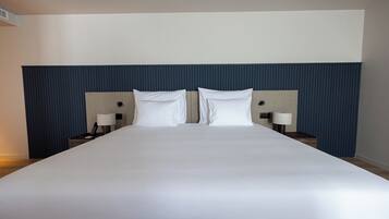 A large bed with a headboard, two bedside tables, and two lamps.