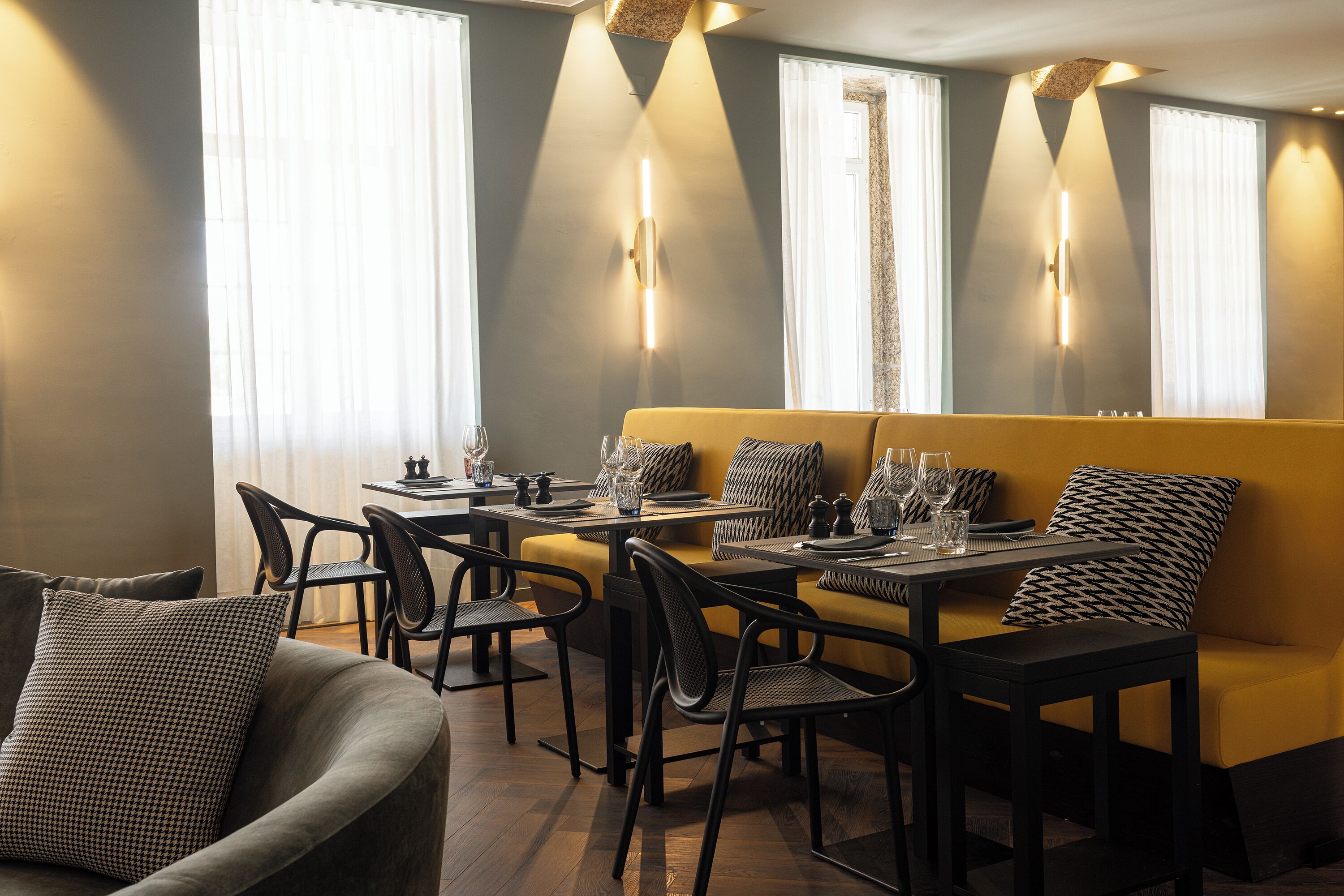 A dining area with a yellow sofa, black chairs, and a table set for four.