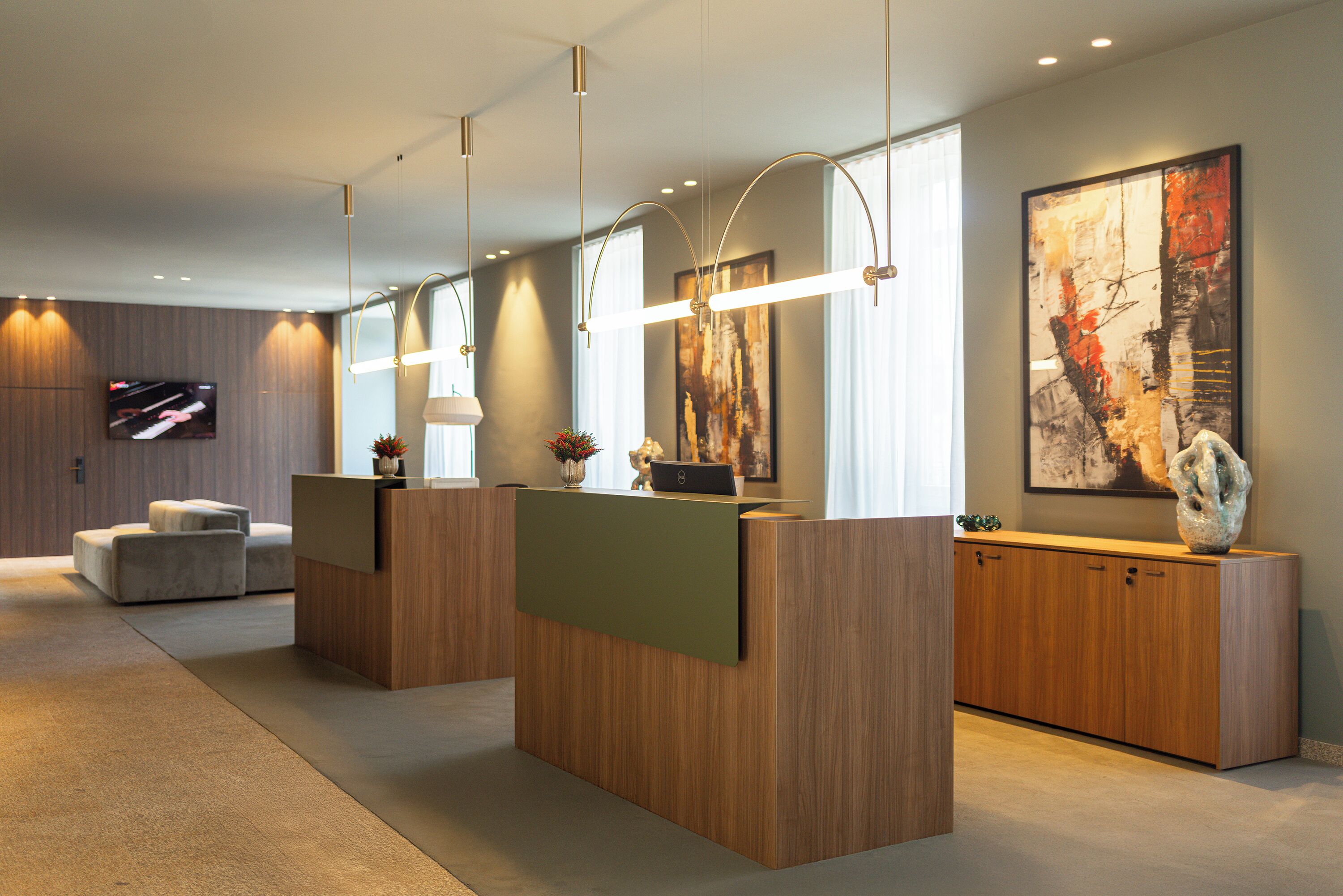 A reception area with a wooden reception desk, a sofa, and a television mounted on the wall.