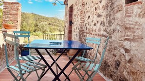 An outdoor patio with a table and chairs, a street lamp, and a rustic building with a tiled roof. - Renovated barn, quiet gîte- Céret (Vivès)