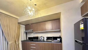 Una cocina moderna con armarios de madera, estufa integrada y un refrigerador negro.