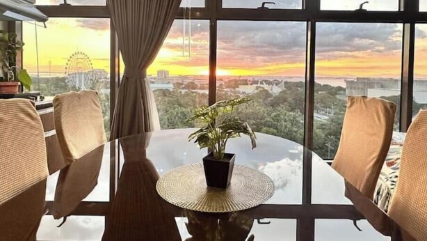 A dining area with a view of a cityscape and a Ferris wheel during sunset. - 10G The Sunset Executive @ The Radiance Manila Bay (Pasay City)