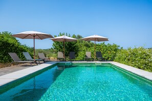 A clear swimming pool with lounge chairs and umbrellas, surrounded by greenery. - Country House 'Els Clepes' with Mountain View, Private Pool and Wi-Fi (Illes Balears)