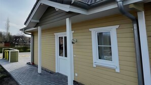 Ein Haus mit gelbem Anstrich, weißem Zierdekor und einem grauen Dach.