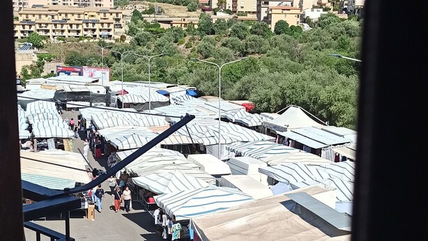 A parking lot with several cars and a market area with tents. - Long Term Vacation Home (Noto)