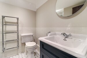 Un baño con una bañera blanca, un inodoro y un toallero de cromo.